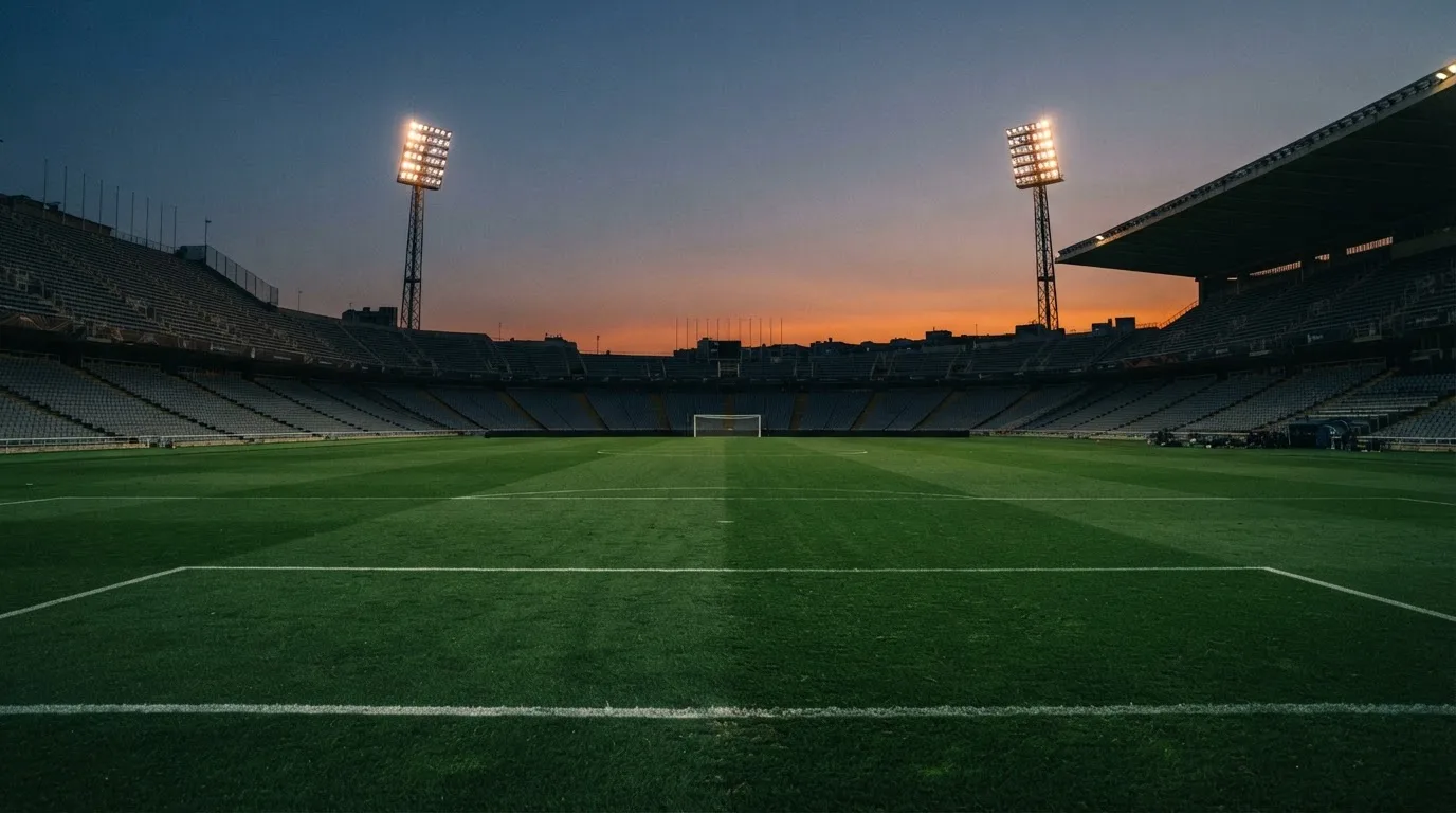 An empty football stadium with floodlight masts at dusk