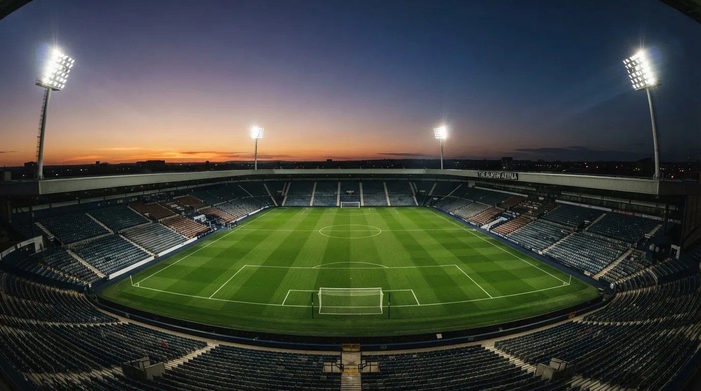 An empty football stadium with floodlight masts at dusk