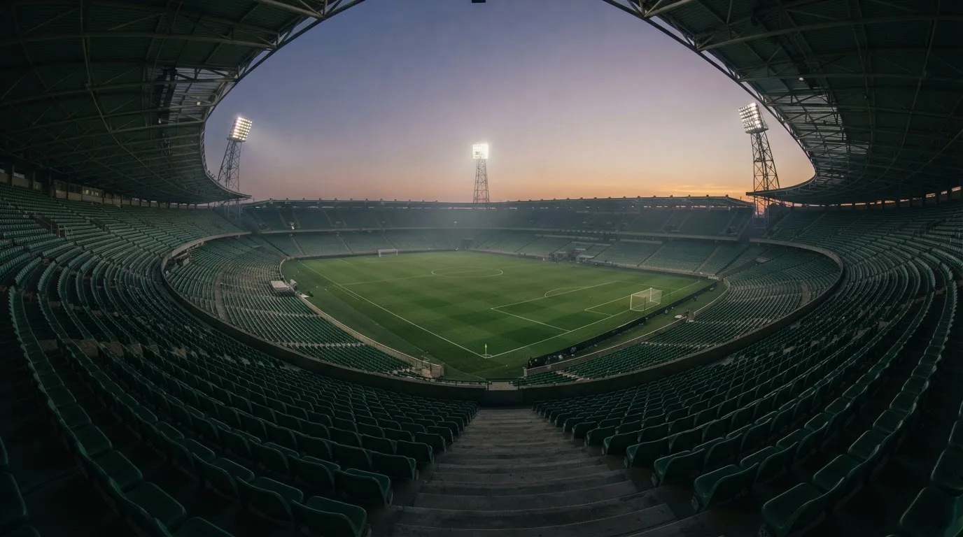 An empty football stadium with floodlight masts at dusk