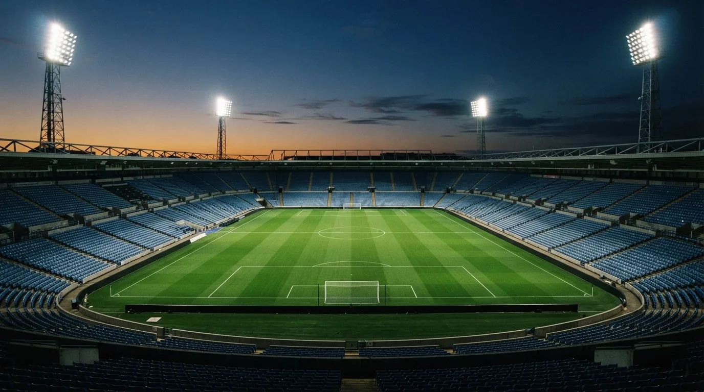 An empty football stadium with floodlight masts at dusk