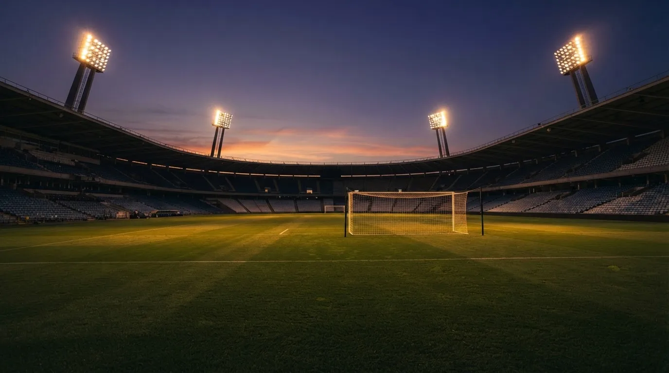 An empty football stadium with floodlight masts at dusk
