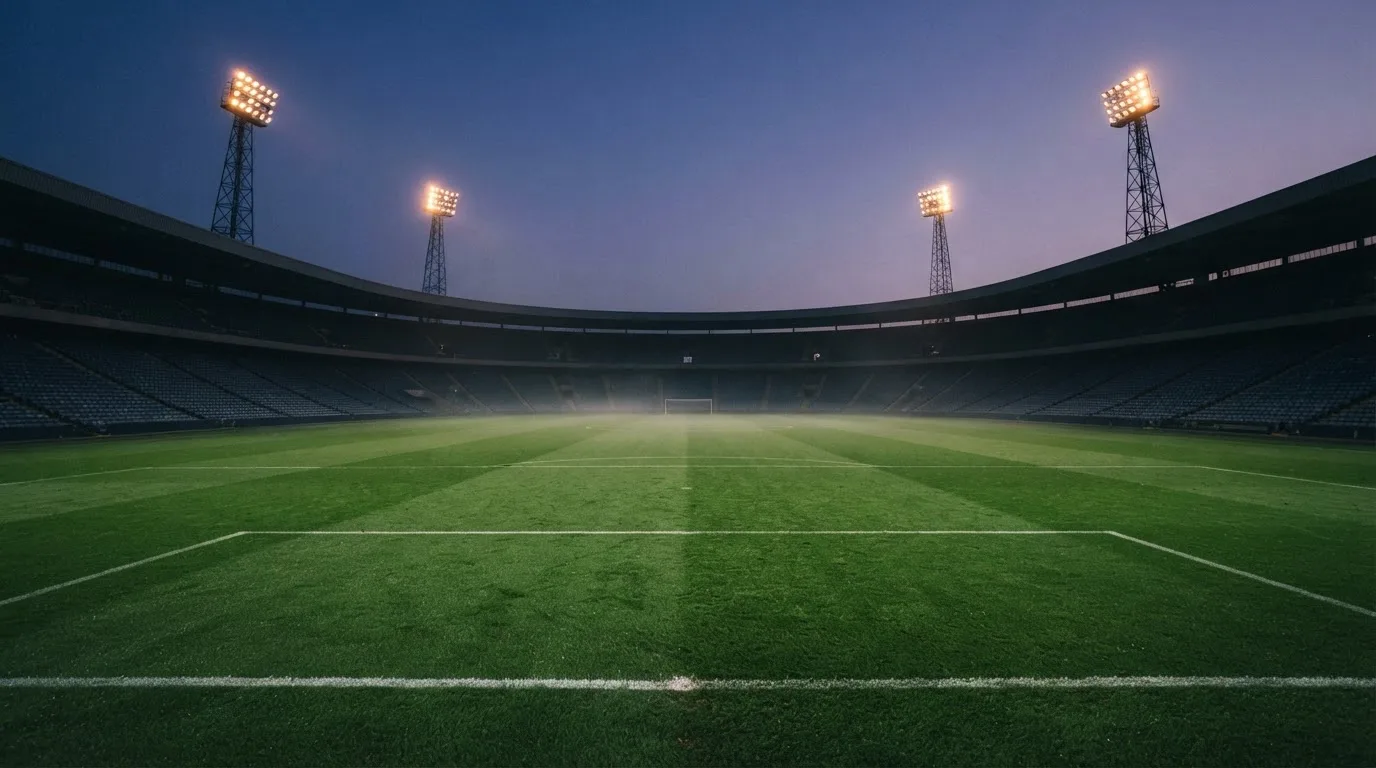 An empty football stadium with floodlight masts at dusk
