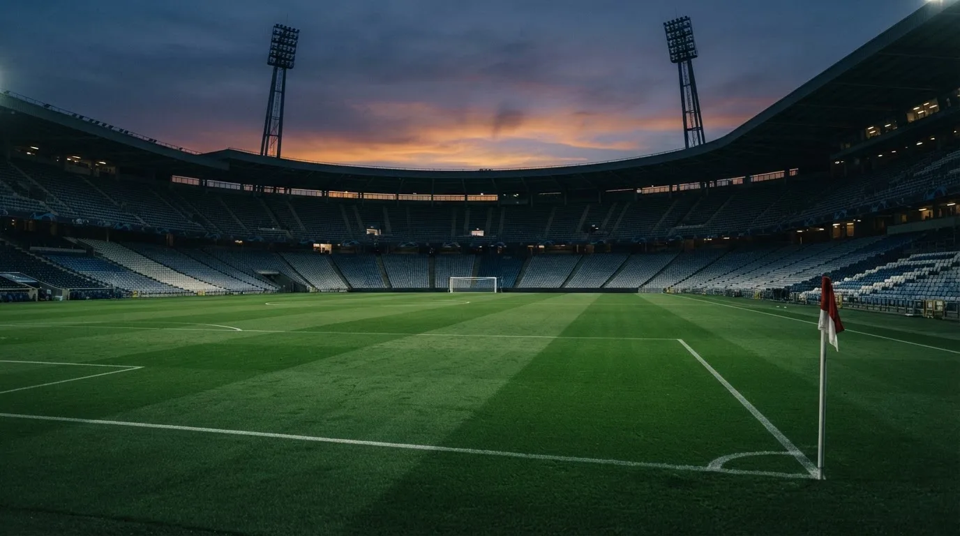 An empty football stadium with floodlight masts at dusk