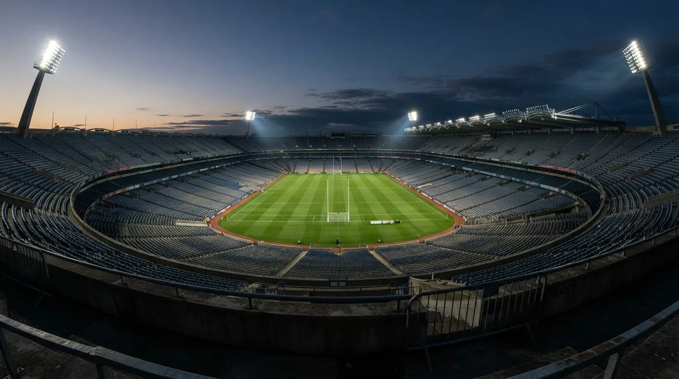An empty football stadium with floodlight masts at dusk