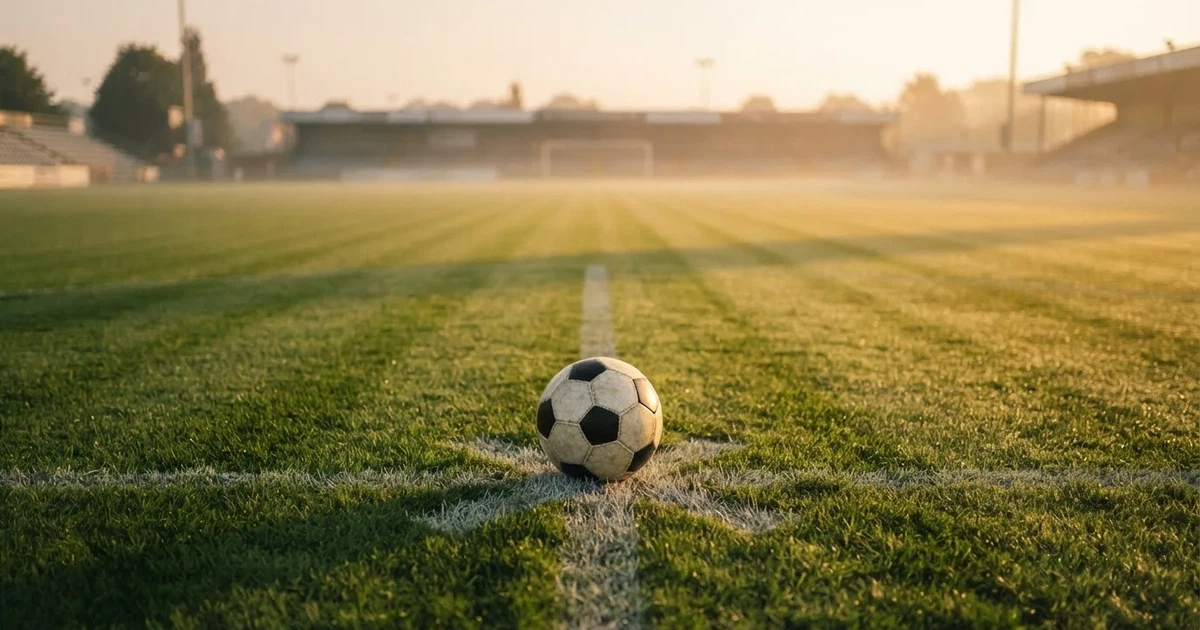 A ball on the centre spot of a grass pitch in morning light