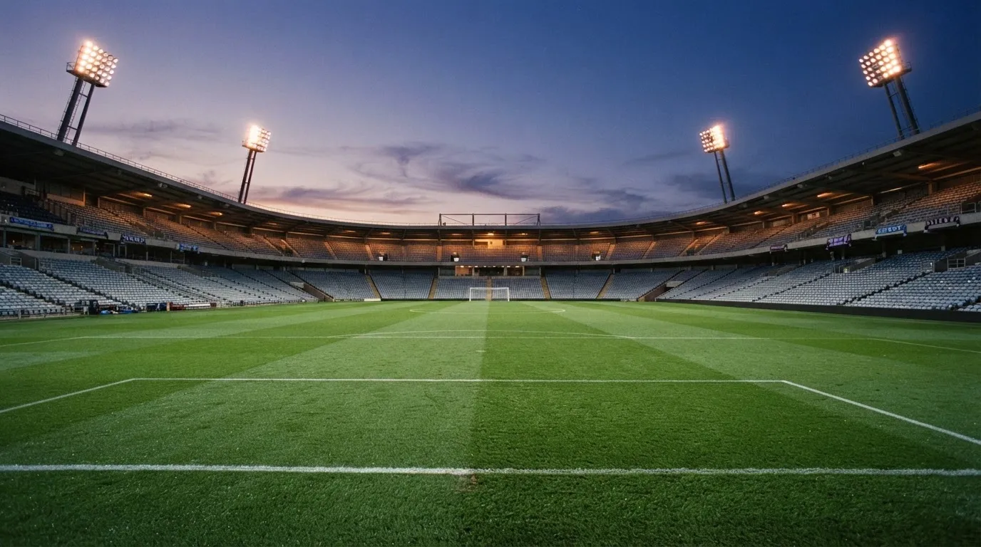 An empty football stadium with floodlight masts at dusk