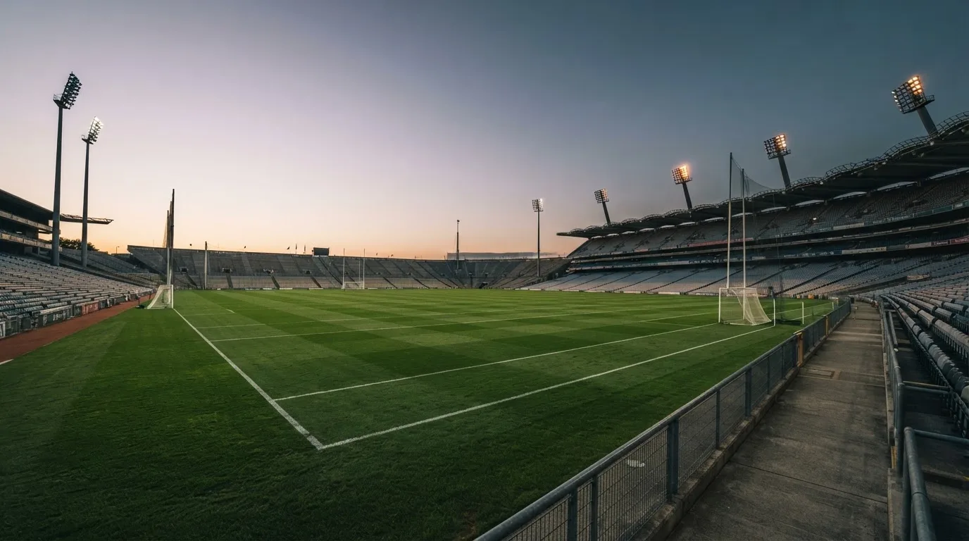 An empty football stadium with floodlight masts at dusk