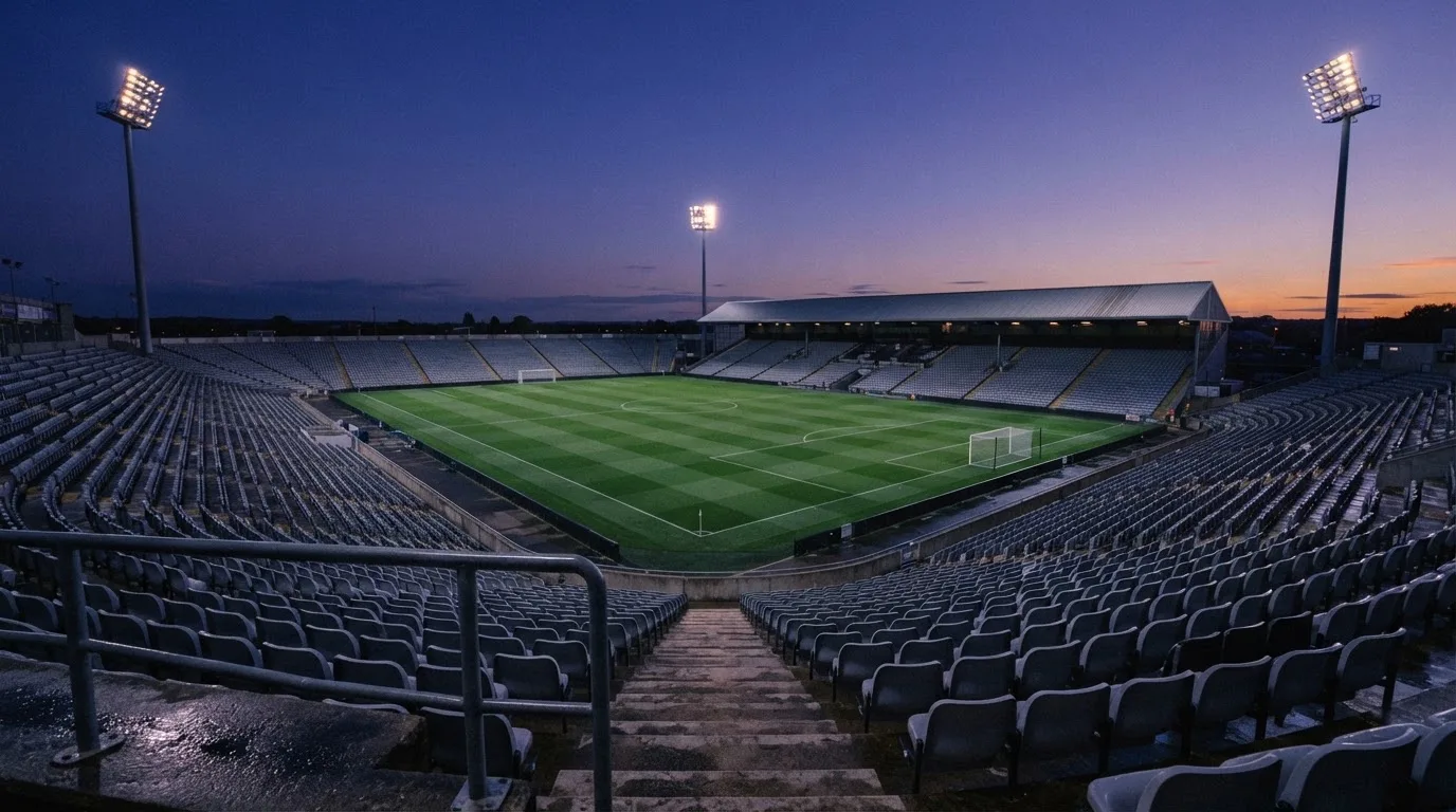 An empty football stadium with floodlight masts at dusk